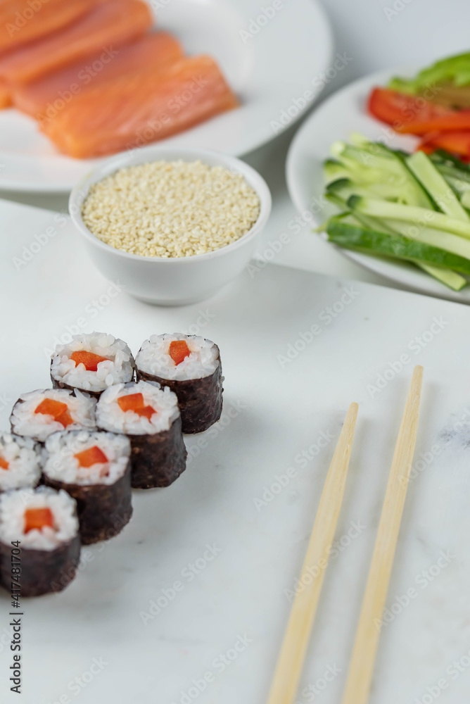 Sushi rolls prepared by professional asian chef with traditional Japanese ingredients. Salmon, rice, vegetables, sesame seeds. Sushi cooking and making concept Sushi rolls prepared by professional asian chef with traditional Japanese ingredients. Salmon, rice, vegetables, sesame seeds. Sushi cooking and making concept