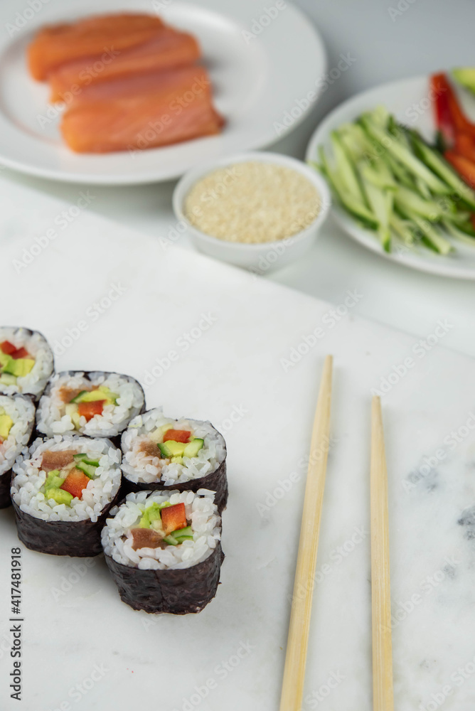 Sushi rolls prepared by professional asian chef with traditional Japanese ingredients. Salmon, rice, vegetables, sesame seeds. Sushi cooking and making concept Sushi rolls prepared by professional asian chef with traditional Japanese ingredients. Salmon, rice, vegetables, sesame seeds. Sushi cooking and making concept