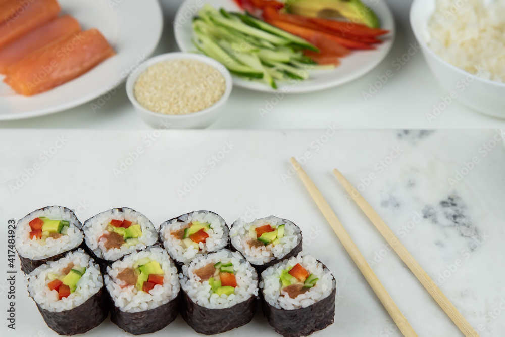 Sushi rolls prepared by professional asian chef with traditional Japanese ingredients. Salmon, rice, vegetables, sesame seeds. Sushi cooking and making concept Sushi rolls prepared by professional asian chef with traditional Japanese ingredients. Salmon, rice, vegetables, sesame seeds. Sushi cooking and making concept