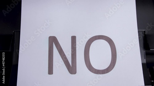 The printer print the word NO on a white sheet. Top view. Close up
