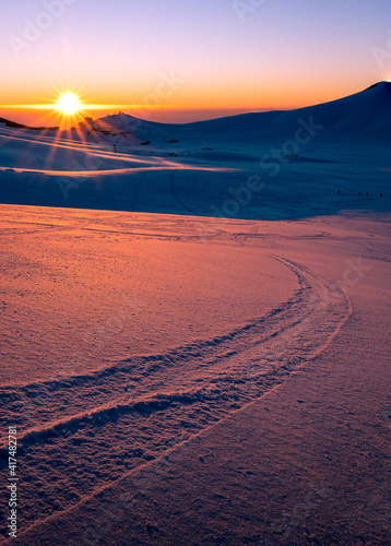 tramonto sulla piana di campocatino innevato. vista sugli impianti sciistici, tracce nella neve