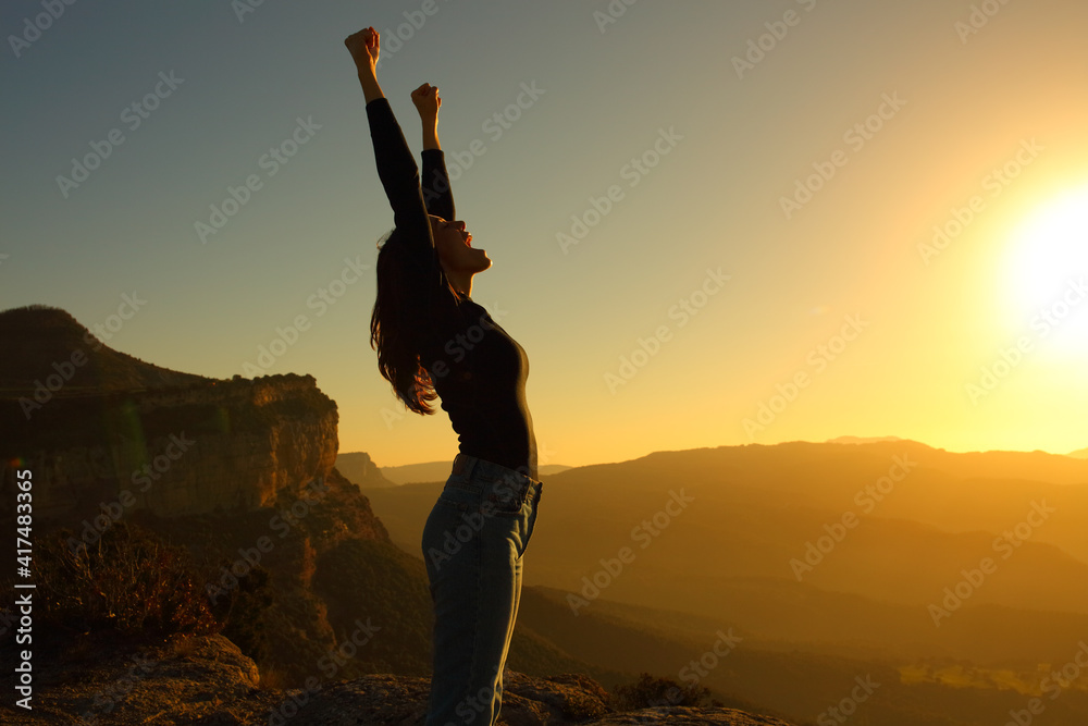 Fototapeta premium Profile of a woman screaming raising arms celebrating sunset