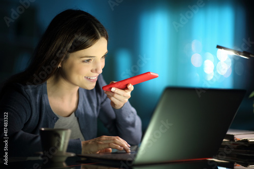 Foto Happy woman using voice recognition on phone in the night