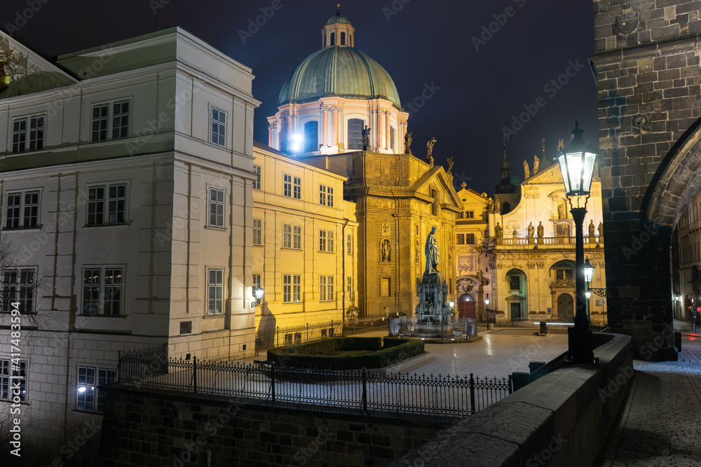 street lighting lamp on Charles Bridge and in the background the monument to Charles IV at the stone tower at night