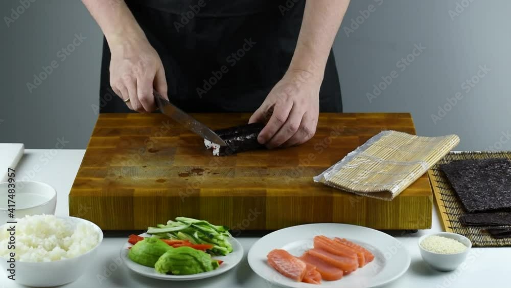 Closeup of chef hands preparing japanese food. Professional chef making sushi at restaurant. Man hands making traditional asian sushi rolls on cutting board. Closeup of chef hands preparing japanese food. Professional chef making sushi at restaurant. Man hands making traditional asian sushi rolls on cutting board.