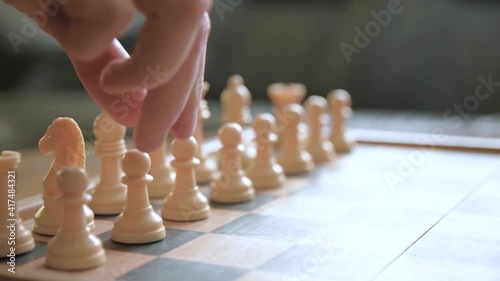 A man moves chess pieces on a chessboard. Against the background of vintage old things. Game of Chess.Player makes a move, developing chess strategy, play board game with opponent.