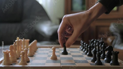 A man moves chess pieces on a chessboard. Against the background of vintage old things. Game of Chess.Player makes a move, developing chess strategy, play board game with opponent.