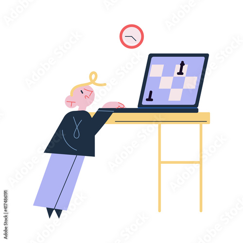 Small boy child standing and playing chess online on laptop on table