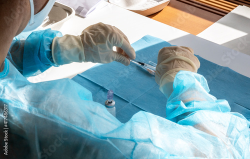 A medical worker prepare an injection of vaccine during a massive vaccination day at a healthcare centre.  Syringes in preparation and ready to use to inoculate the vaccine against the Coronavirus. photo