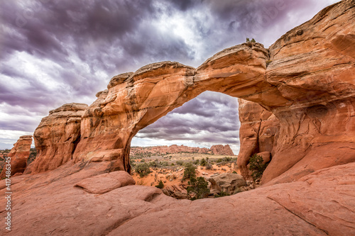 Fotografija The famous Broken Arch in the Arches National Park, Utah and dramatic dark cloud