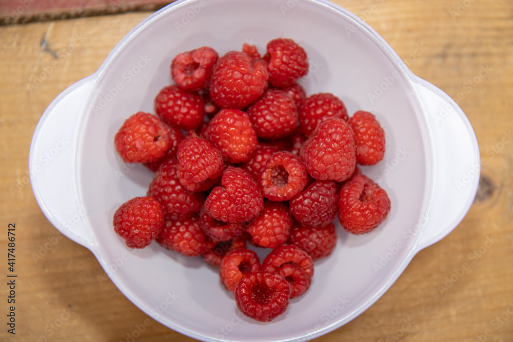 A bowl of delicious red raspberries in a white bowl A bowl of delicious red raspberries in a white bowl