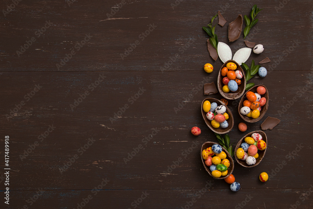 Easter eggs hunt concept background with chocolate Easter eggs on wooden table copy space. View from above