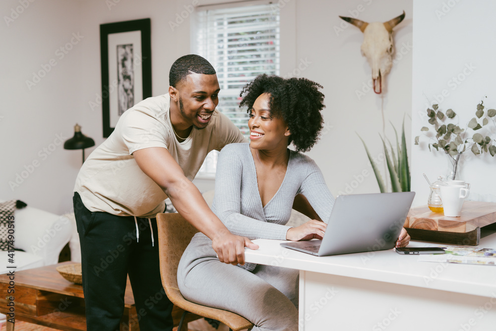 Smiling couple, boyfriend looks over girlfriend shoulder while she works on laptop, intimate moment Smiling couple, boyfriend looks over girlfriend shoulder while she works on laptop, intimate moment