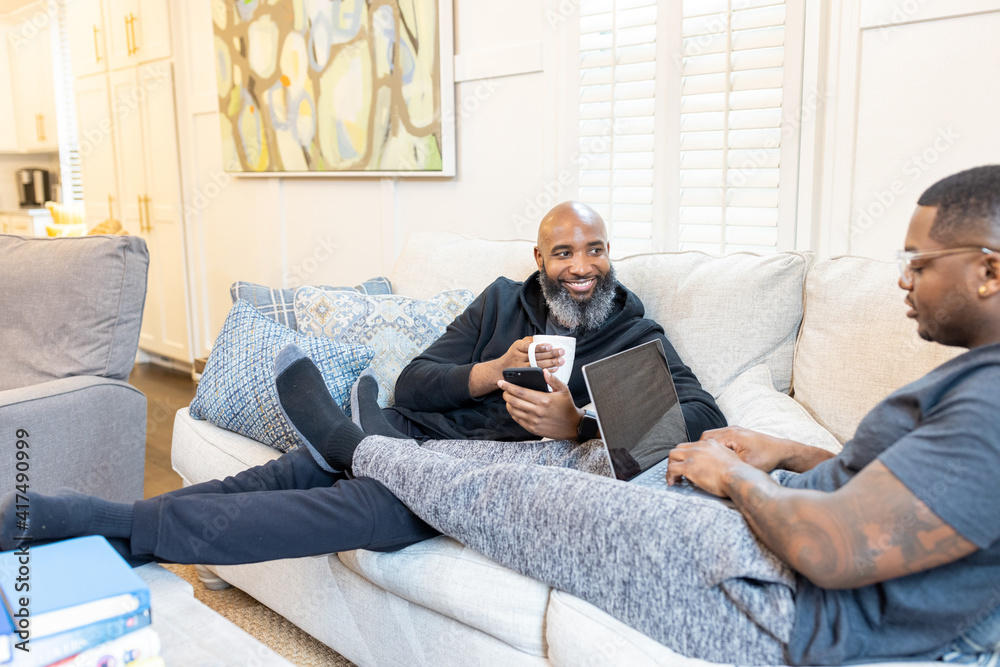 Black gay men have conversations on couch at home Black gay men have conversations on couch at home