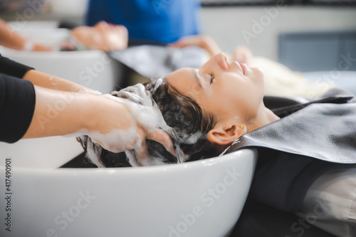 Foto Woman applying shampoo and massaging hair of a customer