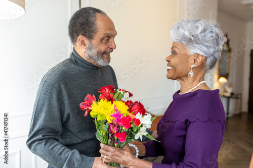 Senior man surprises wife with flowers, celebrating valentines day photo