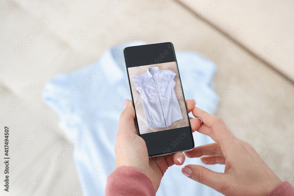 Female hand holds smartphone and makes photos of blue shirt Female hand holds smartphone and makes photos of blue shirt
