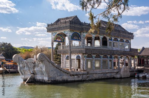 Beijing, China - April 29, 2010: Summer Palace. closeup of emperial boat made of concrete, stone, and marble, docked on green water lake under blue cloudscape. Green foliage.