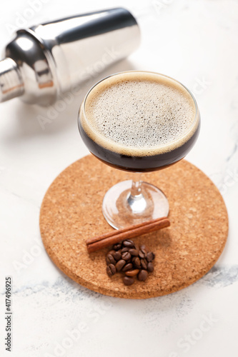 Glass of coffee martini on light background