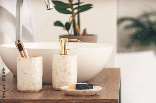 Soap with toothbrushes near sink in bathroom