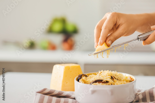Woman grating cheese in kitchen, closeup © Pixel-Shot