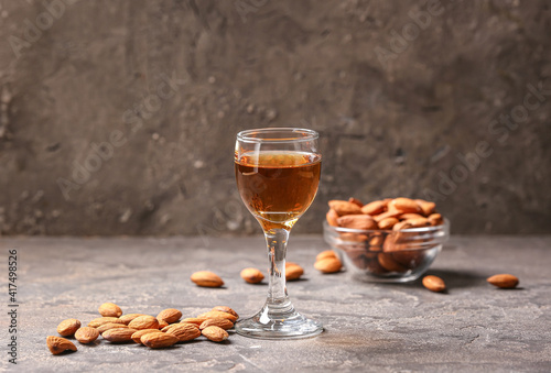 Glass of almond liquor and nuts on dark background