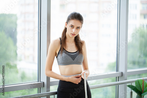 Diet, woman in sportswear measuring her waist, dieting concept