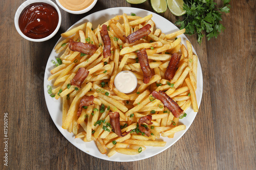 Portion of french fries with bacon. Lettuce, potato, green onion, tomato, ketchup and mayonnaise