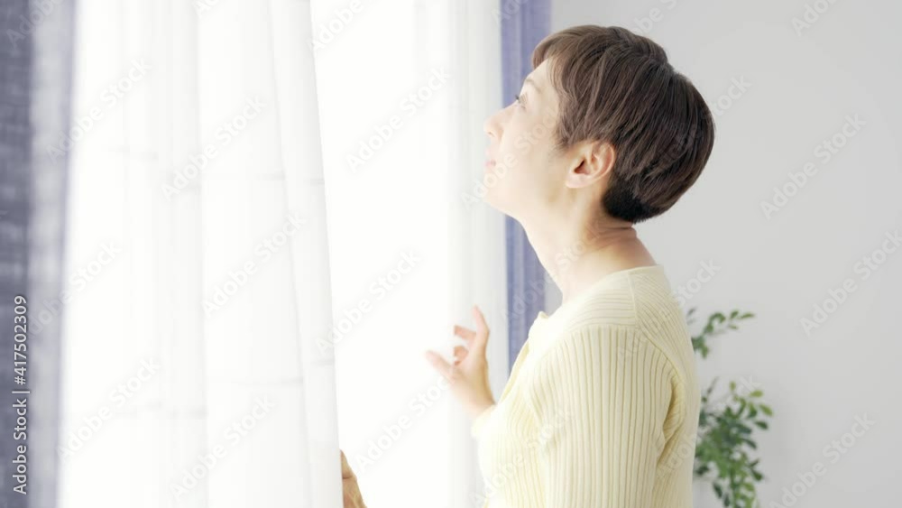 カーテンを開けるミドル女性