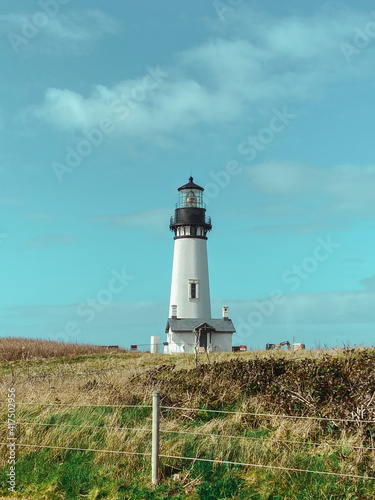 Pacific ocean coastline on a clear sunny day with a black and white historical lighthouse 