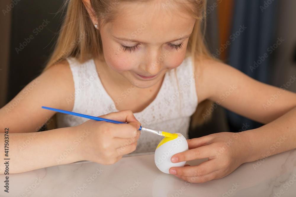 Pretty little girl wearing bunny ears and painting easter eggs at home during coronavirus covid-19 outbreak. Pretty little girl wearing bunny ears and painting easter eggs at home during coronavirus covid-19 outbreak.