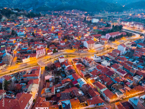 Scenic aerial view of Burdur cityscape with lighted streets and similar brownish tiled roofs on residential buildings in winter twilight, Turkey