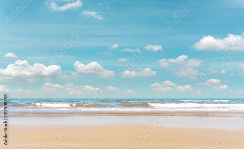 Golden sand beach on blue sea under white clouds pastel blue sky © Arunee