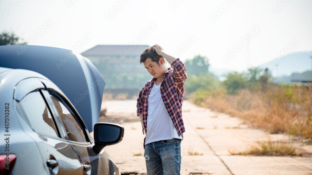 A young man open the bonnet while analyzing the breakdown of the car. A young man open the bonnet while analyzing the breakdown of the car.
