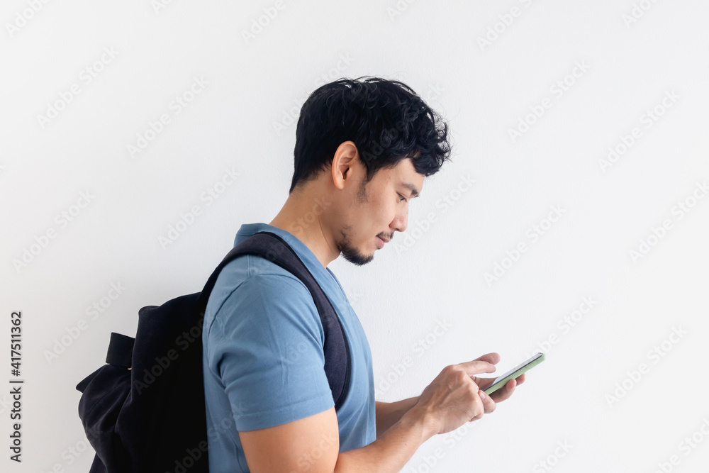Asian man traveler with a backpack is using a mobile phone application. Asian man traveler with a backpack is using a mobile phone application.
