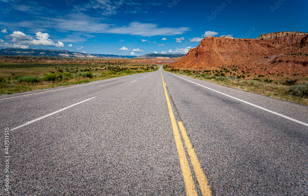Straight highway cuts though the Abiquiu area with red rocks of fire. Straight highway cuts though the Abiquiu area with red rocks of fire.