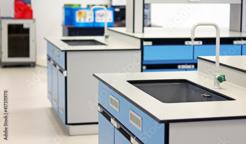 Blue sink with tap water set up into Bench lab in chemistry laboratory room. White Faucet with drop of water flowing into sink in laboratory, use for cleaning or washing hands prevent coronavirus.