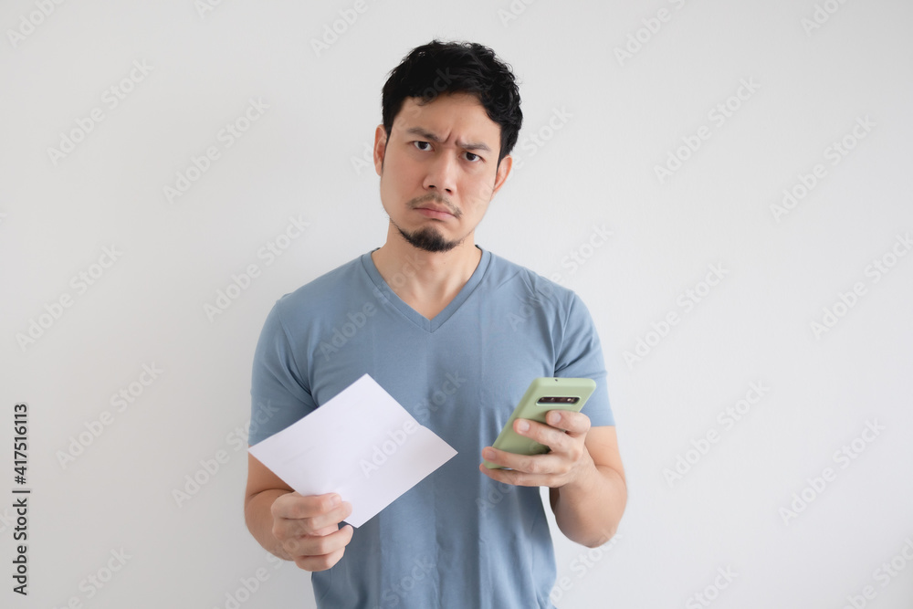 Asian man is serious by the bill and the smartphone on isolated background. Asian man is serious by the bill and the smartphone on isolated background.