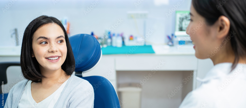 Caucasian girl consulting Asian female dentist about oral care checkup