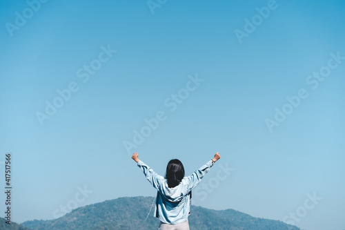 Copy space of woman raise hand up on top of mountain and blue sky cloud abstract background. Freedom feel good and travel adventure holiday concept.