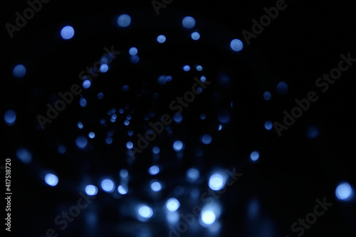 Blurred background with a cool blue glow in the dark. Glowing Christmas garland in bokeh. Blank for the background.