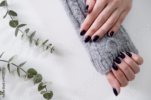Women's hands. Manicure in dark blue with sparkles. Blue nails. Delicate nail polish.