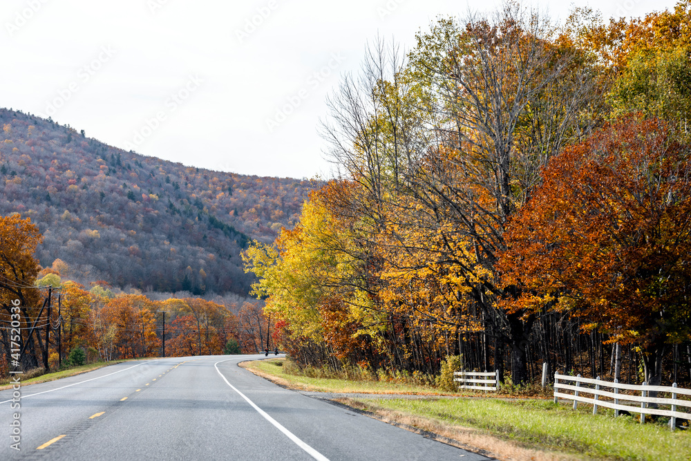 Winding road in the Vermont mountains with autumn yellowed maple trees along the road and on the mountains