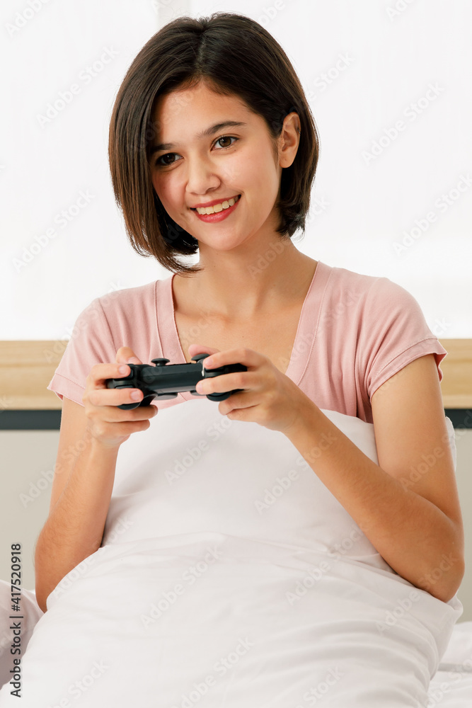 Adult beautiful asian woman are pretty with short hair and wearing pink t-shirt holding joystick and hug pillow playing game and and joining video game console look and casual in morning on day Adult beautiful asian woman are pretty with short hair and wearing pink t-shirt holding joystick and hug pillow playing game and and joining video game console look and casual in morning on day