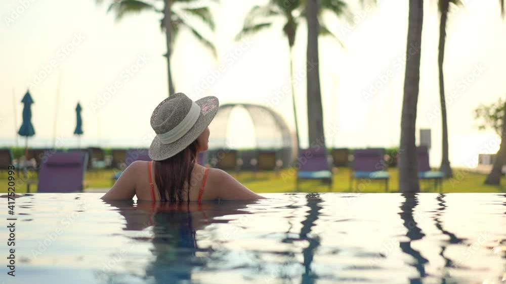 Back view of woman in pool looking at garden. Slow-motion