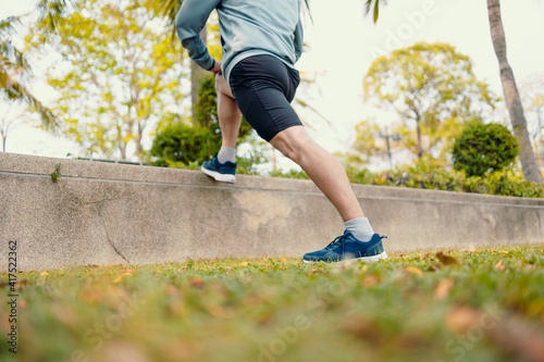 Attractive young man stretching in the park before running. Young man workout before fitness training at the park. Healthy and exercise young man warming up.