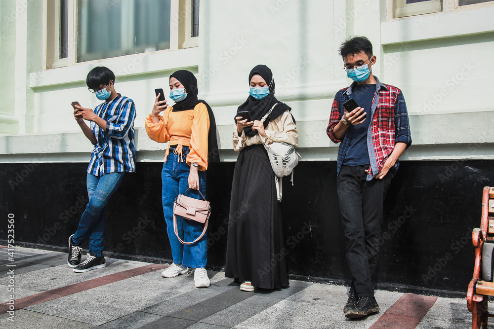 Group of young group people using mobile cell phones to watch content in the new normality time during coronavirus pandemic. Millennial generation people always connected concept
