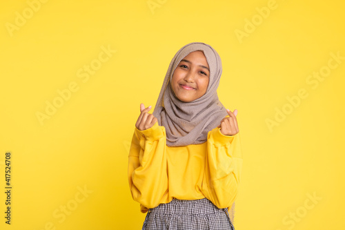Fashion portrait of young beautiful asian muslim woman with wearing hijab isolated on yellow background
