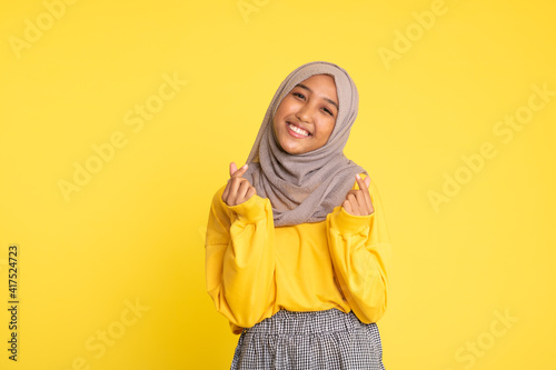 Fashion portrait of young beautiful asian muslim woman with wearing hijab isolated on yellow background © faishalabdula