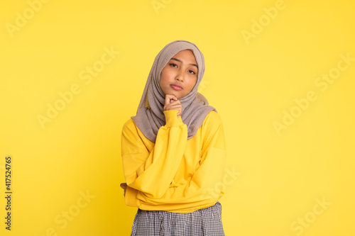 Fashion portrait of young beautiful asian muslim woman with wearing hijab isolated on yellow background © faishalabdula